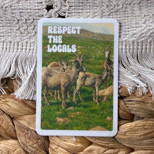 May include: A rectangular sticker with the text "RESPECT THE LOCALS" in white block letters. The sticker features a drawing of a herd of mountain goats in a grassy field. The sticker is on a woven background.