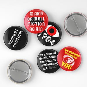 May include: A collection of round buttons with various designs and text. One button reads "THOUGHT CRIMINAL" in white on black. Others feature phrases like "MAKE ORWELL FICTION AGAIN" and "BIG BROTHER is watching YOU".