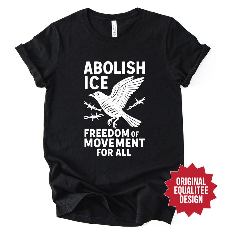 May include: Black t-shirt with a white graphic of a bird breaking through barbed wire, with the words "ABOLISH ICE" and "FREEDOM OF MOVEMENT FOR ALL". The shirt also has a red star-shaped design that says "ORIGINAL EQUALITEE DESIGN".