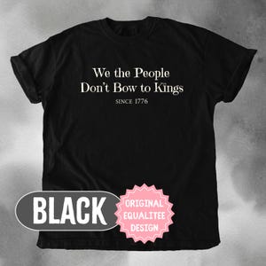 K&ouml;nnte beinhalten: Schwarzes T-Shirt mit dem wei&szlig;en Text "We the People Don't Bow to Kings" und "Since 1776". Das Shirt hat auch ein schwarzes Oval mit dem Wort "BLACK" und einen rosa Stern mit "ORIGINAL EQUALITEE DESIGN".