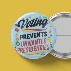 May include: A light blue button with the words "Voting Prevents Unwanted Presidencies" in black and red text. The button is decorated with colorful floral designs and has a silver metal backing.