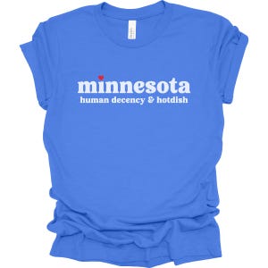 May include: A blue t-shirt with white text that reads "minnesota human decency & hotdish" with a small red heart above the word "minnesota".