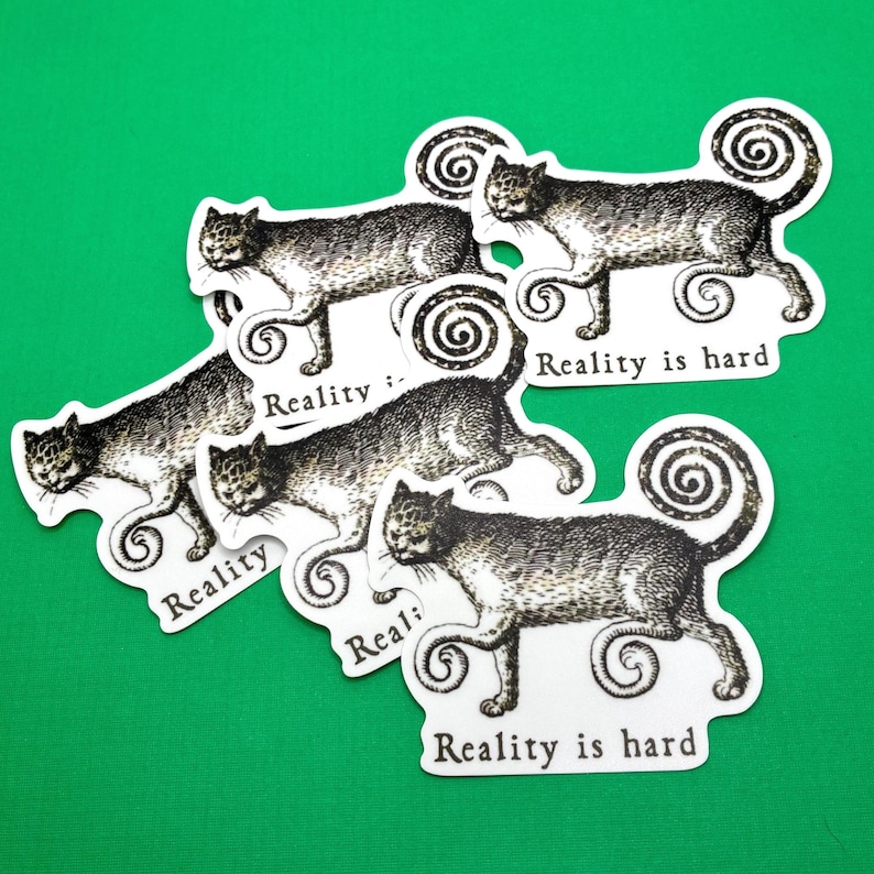 May include: A collection of cat stickers with a vintage illustration style. The cats are depicted in shades of gray and black, with a whimsical, curly tail design. Each sticker has the text "Reality is hard".