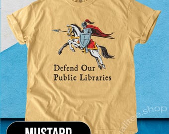 May include: A mustard yellow t-shirt with a graphic of a knight on horseback holding a spear and shield. The text "Defend Our Public Libraries" is printed below the graphic.
