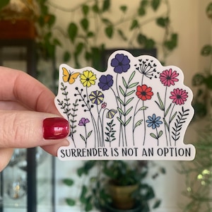 May include: A white sticker with a colourful floral design and the text "Surrender is not an option".