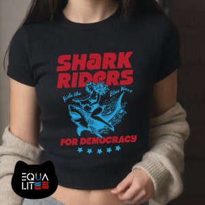 Shark Riders for Democracy Baby Tee | Ride the Blue Wave | Girl Riding Shark Design, Shark T-Shirt, Stormy T-shirt, Shark T-shirt