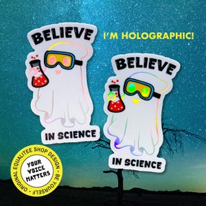 May include: Two holographic stickers featuring a ghost character wearing goggles and holding a flask. The stickers read "BELIEVE IN SCIENCE" and "I'M HOLOGRAPHIC!" The stickers have a white background and a colorful, iridescent effect.