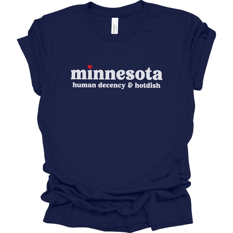 May include: A navy blue t-shirt with white text that reads "minnesota human decency & hotdish" with a small red heart above the word "minnesota".
