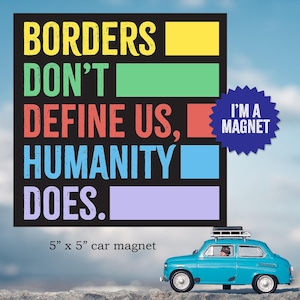 May include: A blue car magnet with the text "Borders don't define us, humanity does." and "I'm a magnet" in a starburst shape. The magnet is 12.7 cm by 12.7 cm.
