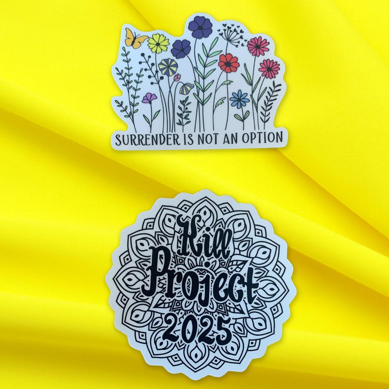 May include: Two stickers on a yellow background. The first sticker features a black and white mandala with the text "Kill Project 2025" in black. The second sticker features a black and white illustration of flowers and butterflies with the text "Surrender is not an option" in black.