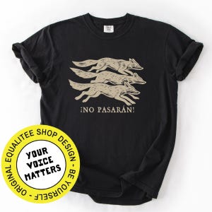 May include: Black t-shirt featuring a graphic of three running coyotes in a tan color, with the Spanish phrase "&iexcl;NO PASAR&Aacute;N!" printed below. The shirt has a classic crew neck and short sleeves.