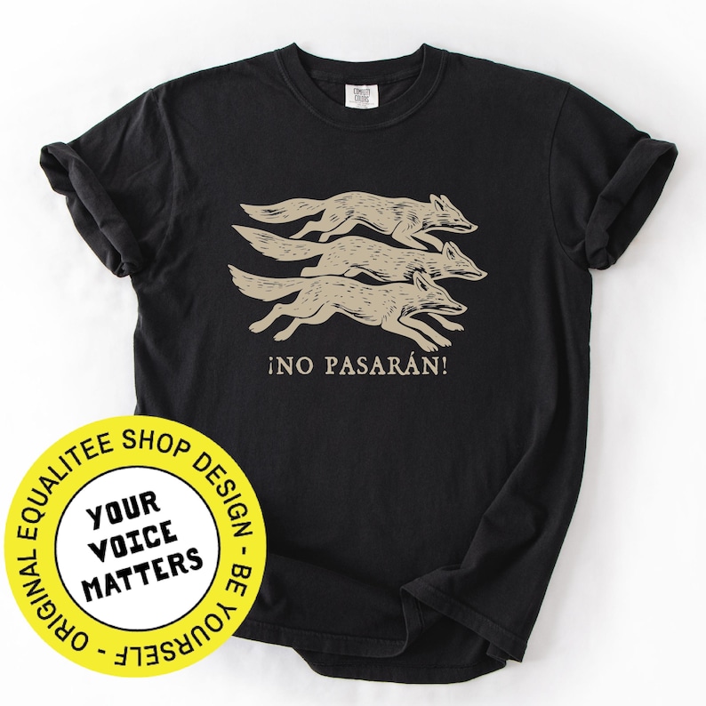 May include: Black t-shirt featuring a graphic of three running coyotes in a tan color, with the Spanish phrase "&iexcl;NO PASAR&Aacute;N!" printed below. The shirt has a classic crew neck and short sleeves.