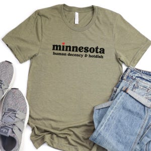 May include: A green t-shirt with the text "minnesota human decency & hotdish" in black with a red heart above the word "minnesota".
