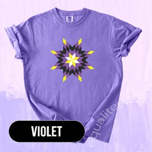 May include: Violet-colored t-shirt featuring a geometric star design in yellow, black, and purple. The shirt has rolled-up sleeves and the word "VIOLET" in a black oval at the bottom. The shirt is a comfortable, casual style.