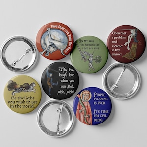 May include: A collection of round pinback buttons with medieval-style illustrations and humorous text. The buttons feature various colors, including red, green, and blue, with phrases like "Thou Shall Lick Butts Not Boots" and "People Pleasing Is Over."