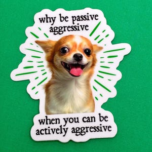 Pu&ograve; includere: Un adesivo bianco con un cane Chihuahua sorridente e il testo "why be passive aggressive when you can be actively aggressive" in nero. Il cane &egrave; marrone e bianco con la lingua di fuori, e linee verdi irradiano da dietro.