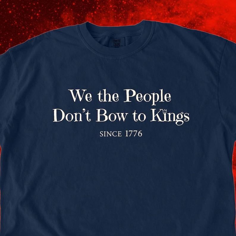 K&ouml;nnte beinhalten: Marineblaues T-Shirt mit dem wei&szlig;en Text "We the People Don't Bow to Kings SINCE 1776". Das T-Shirt hat einen Rundhalsausschnitt und kurze &Auml;rmel. Der Text ist mittig auf der Vorderseite des Shirts platziert.