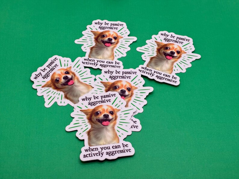 Pu&ograve; includere: Una collezione di adesivi con un cane Chihuahua sorridente e il testo "why be passive aggressive when you can be actively aggressive" su sfondo verde. Gli adesivi hanno un bordo bianco e un design a raggi.