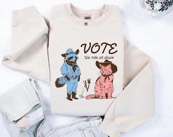 VOTE We Ride At Dawn Shirt & Sweatshirt, Cute Raccoon Cat Cowboy T-Shirt, Progressive Political Tee, Wild West Election Comfort Colors Top