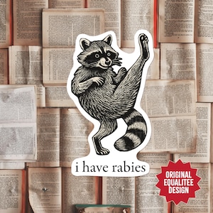 May include: A black and white sticker featuring a raccoon in a karate pose with the text "i have rabies". The sticker has a striped tail and is set against a background of open books. The sticker also has a red starburst with the text "ORIGINAL EQUALITEE DESIGN".