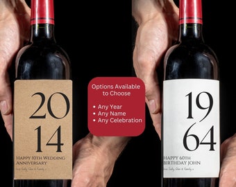 May include: Two wine bottles with personalized labels. The bottle on the left has a brown label with the numbers "2014" and the text "Happy 10th Wedding Anniversary". The bottle on the right has a white label with the numbers "1964" and the text "Happy 60th Birthday John".