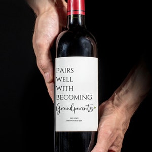 May include: A bottle of red wine with a white label that reads "Pairs well with becoming Grandparents" and "Baby Jones Arriving August 2024".