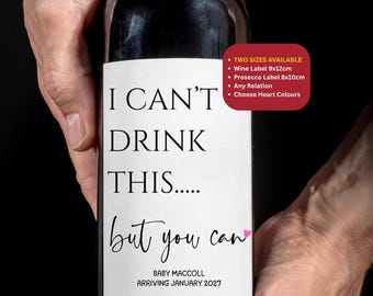 May include: A wine bottle with a custom label that reads "I CAN'T DRINK THIS... but you can" with the text "BABY MACCOLL ARRIVING JANUARY 2027". The label also includes a pink heart and a list of options.