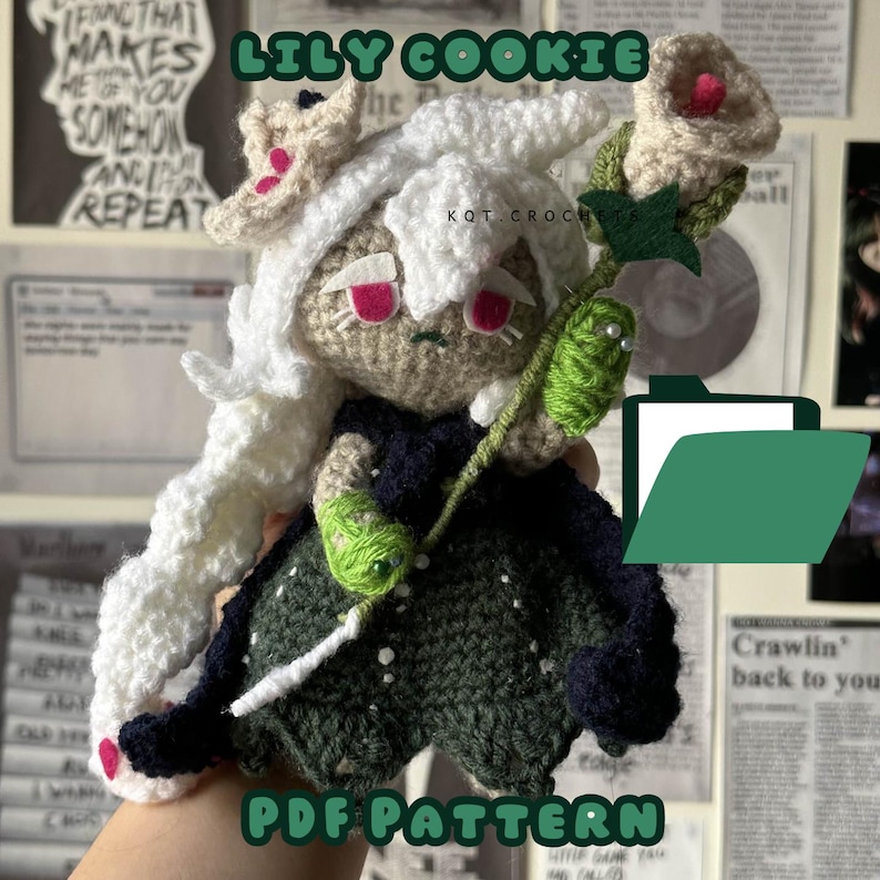 May include: Crocheted amigurumi doll of Lily Cookie from the Cookie Run: Kingdom mobile game. The doll is wearing a green and black dress and holding a white flower. The doll is sitting on a hand and the text "Lily Cookie" and "PDF Pattern" are visible in the image.