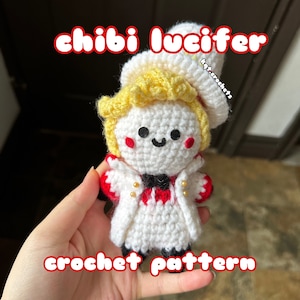 May include: A crocheted amigurumi doll of Lucifer from the anime series "Obey Me!" The doll is wearing a white coat with red accents and a black bow tie. The doll has yellow hair and a smiling face.