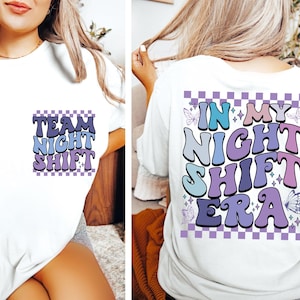 以下が含まれることがあります： 白地に紫と青のグラフィックがプリントされたTシャツ。前面には「Team Night Shift」、背面には「In My Night Shift Era」と書いてある。グラフィックは市松模様の背景と星で飾られている。