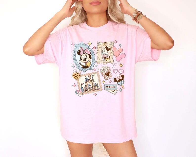 Pu&ograve; includere: T-shirt rosa chiaro con un design a collage di cartoni animati. Il design include Minnie Mouse, un castello, popcorn, gelato e la parola "MAGIC". Le illustrazioni sono incorniciate con bordi decorativi e stelle.