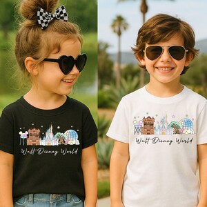 May include: A black t-shirt and a white t-shirt, each featuring a colorful graphic illustration of Walt Disney World landmarks including the castle, the tree, and the sphere, with the text Walt Disney World printed in a black cursive script.