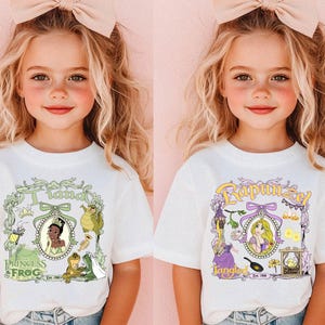Pu&ograve; includere: Due magliette bianche con grafiche a cartoni animati di principesse Disney. Una maglietta mostra "Tiana" con una cornice verde e personaggi de "La principessa e il ranocchio". L'altra maglietta mostra "Rapunzel" con una cornice viola e personaggi di "Rapunzel - L'intreccio della torre".
