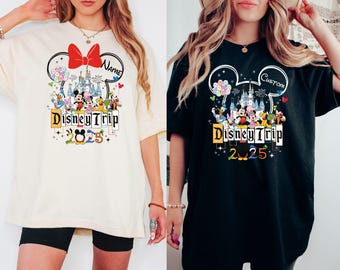 May include: Two women wearing white and black t-shirts with a Mickey Mouse ear design. The shirts feature a graphic of Mickey Mouse and other Disney characters in front of Cinderella's Castle. The text "Disney Trip 2025" is printed on the shirts. One shirt says "Name" and the other says "Custom".