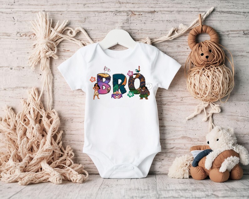 K&ouml;nnte beinhalten: Wei&szlig;er Baby-Strampler mit einem bunten Grafikdruck des Wortes "BRO" mit Figuren aus dem Animationsfilm Vaiana.