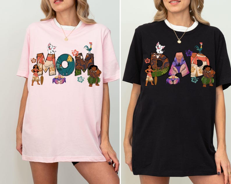 K&ouml;nnte beinhalten: Zwei T-Shirts, eines rosa und eines schwarz, mit einem grafischen Design, das die W&ouml;rter "MOM" und "DAD" in einer stilisierten Schrift zeigt. Die Buchstaben sind mit Figuren aus dem Animationsfilm Vaiana verziert, darunter Maui, Pua und Hei Hei.