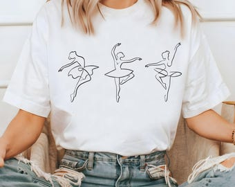 Könnte beinhalten: Weißes T-Shirt mit einer einfachen Linienzeichnung von drei Ballerinas in verschiedenen Posen.