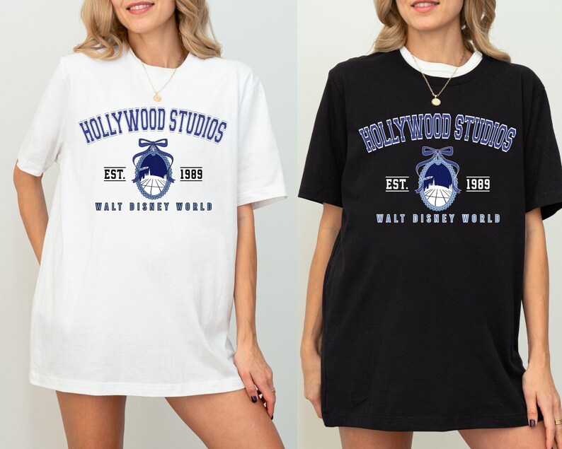Puede incluir: Camisetas blancas y negras con el texto "HOLLYWOOD STUDIOS" en azul, un gr&aacute;fico a juego y el texto "EST. 1989 WALT DISNEY WORLD". Las camisetas son de manga corta y tienen un corte holgado.