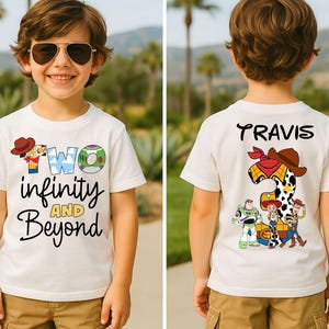 Może przedstawiać: Biała koszulka z napisem "TWO infinity AND Beyond" i grafiką z kreskówek. Tył koszulki ma imię "Travis" i grafikę z numerem 2 z postaciami z Toy Story. Koszulka jest noszona przez małego chłopca.