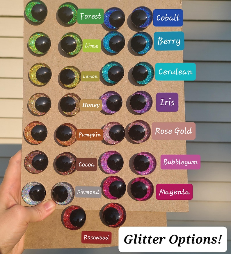 May include: A display of 16 different glitter colors for craft eyes. The colors are: Forest, Cobalt, Berry, Lime, Cerulean, Lemon, Iris, Honey, Rose Gold, Pumpkin, Cocoa, Diamond, Bubblegum, Magenta, and Rosewood. The text "Glitter Options!" is at the bottom of the display.