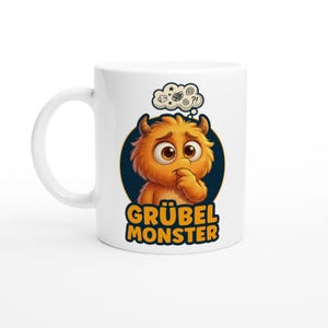 Peut inclure: Tasse en céramique blanche avec un dessin de monstre de dessin animé. Le monstre orange a une expression inquiète et réfléchit. La tasse porte les mots "GRÜBEL MONSTER" en jaune et un fond bleu.
