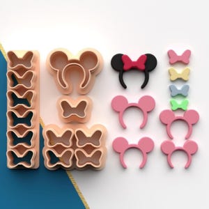 May include: A set of 12 pink and white plastic cookie cutters in the shape of bows, headbands, and mouse ears. The cutters are arranged in a row on a white surface.