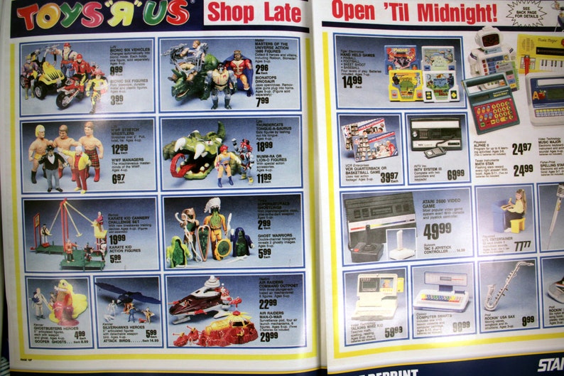 May include: A Toys 'R' Us advertisement page featuring various toys and electronics. The page includes action figures, video games, and educational toys. The text "Shop Late Open 'Til Midnight!" is visible at the top of the page.