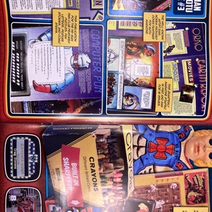 May include: A vintage magazine spread featuring He-Man and the Masters of the Universe. The layout includes comic strips, fan club content, and Crayola crayons. The magazine cover is titled "1985 He-Man and the MOTU Magazine #3."