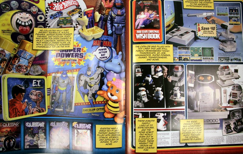 May include: A vintage advertisement spread from the 1986 Sears Christmas Wish Book. The pages showcase toys, including Hot Wheels cars, E.T. lunchboxes, Batman figures, and a Nintendo Entertainment System. The catalog also features robots and other collectibles.