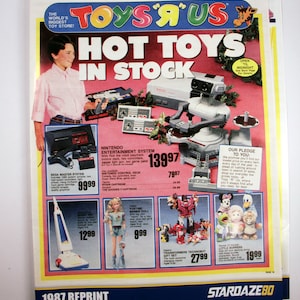 May include: A vintage Toys 'R' Us advertisement featuring a boy and various toys. The ad showcases a Nintendo Entertainment System, Sega Master System, Barbie doll, Transformers, and other items. The headline reads "Hot Toys In Stock."
