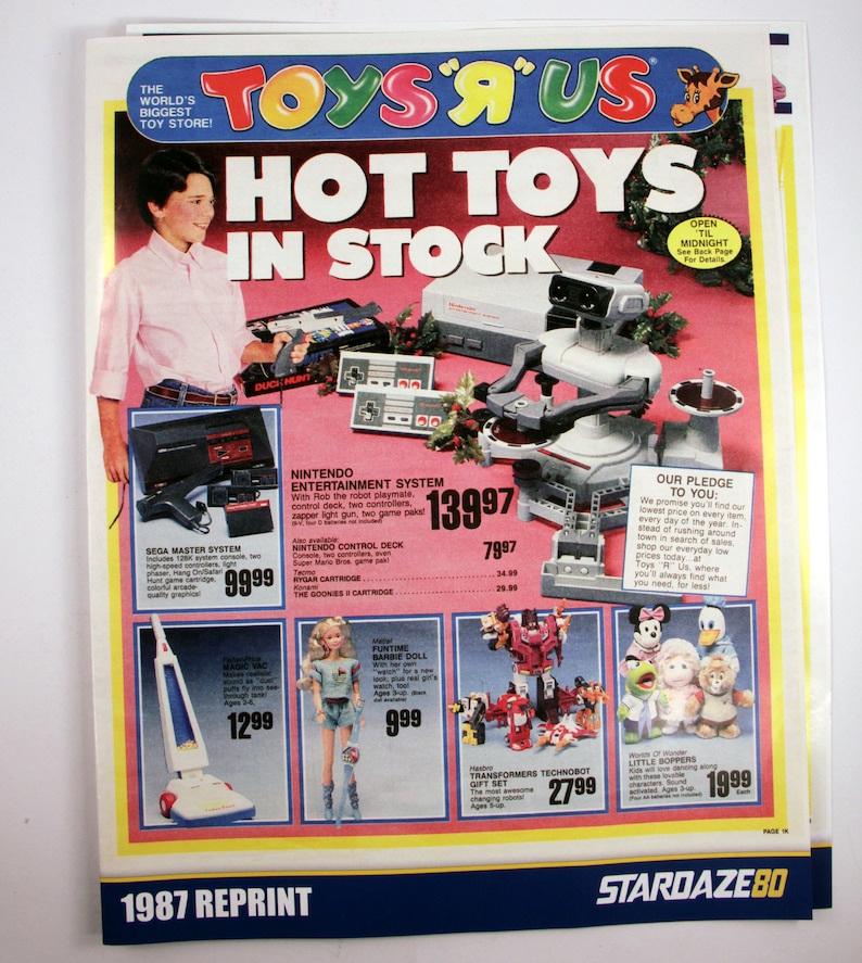 May include: A vintage Toys 'R' Us advertisement featuring a boy and various toys. The ad showcases a Nintendo Entertainment System, Sega Master System, Barbie doll, Transformers, and other items. The headline reads "Hot Toys In Stock."