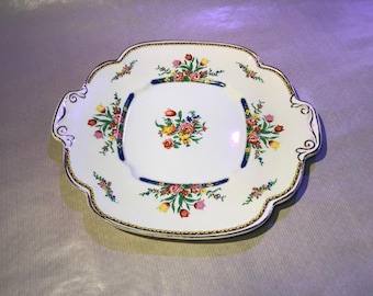 May include: A white oval serving platter with a gold rim and floral design. The flowers are in shades of pink, yellow, and blue.