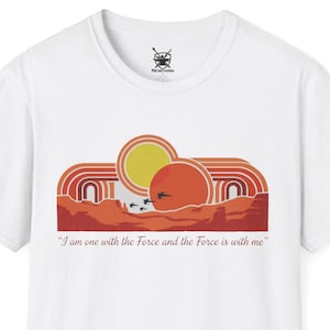 Op de afbeelding: Wit T-shirt met een retro graphic van een zon en woestijnlandschap in oranje, rood en geel. De tekst luidt: "I am one with the Force and the Force is with me." Een eenvoudig, stijlvol ontwerp.
