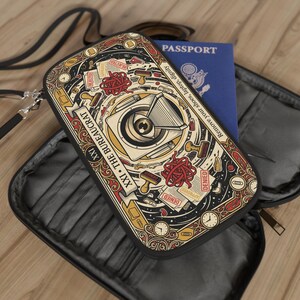 May include: A rectangular travel document organizer featuring a black, red, and gold graphic print titled XXI THE BUREAUCRAT. The design includes an eye, stamps, tangled red lines, and the text Remove your shoes, laptop, dignity. A blue passport is inside.